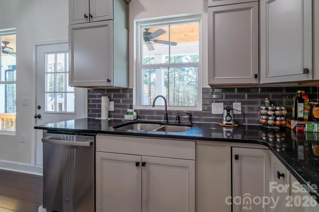 a kitchen with stainless steel appliances granite countertop a sink a window and cabinets