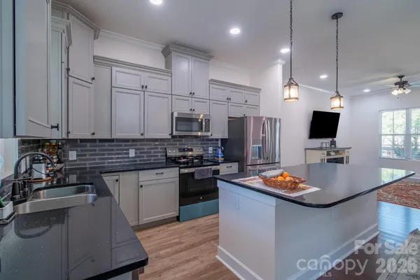 a kitchen with stainless steel appliances kitchen island granite countertop a sink a stove and a refrigerator