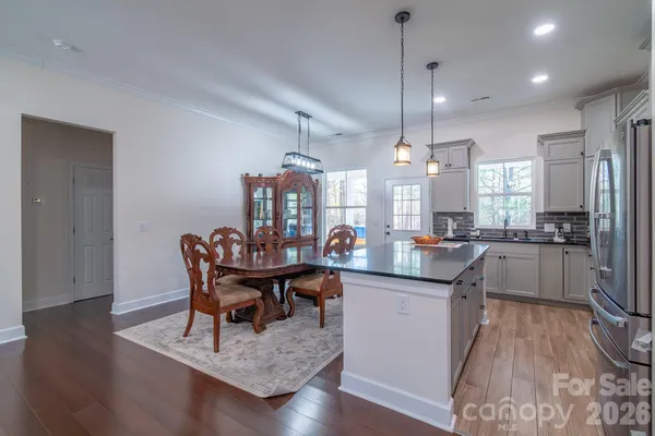 a view of a dining room and livingroom with furniture wooden floor a chandelier