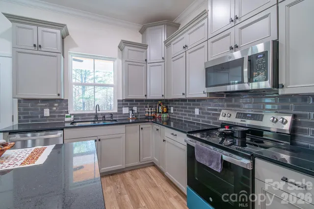 a kitchen with stainless steel appliances granite countertop a stove a sink and a microwave