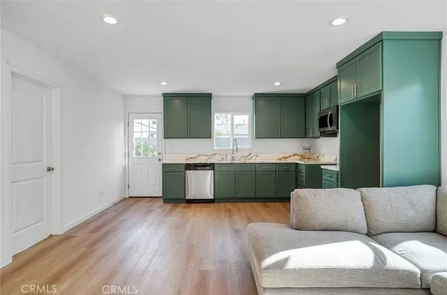 a living room with stainless steel appliances kitchen island granite countertop furniture and a large window