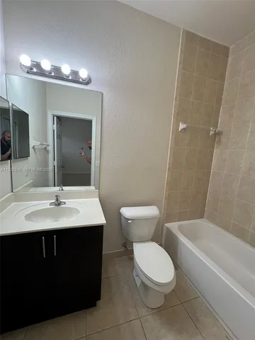 a bathroom with a toilet a sink a large mirror and bathtub