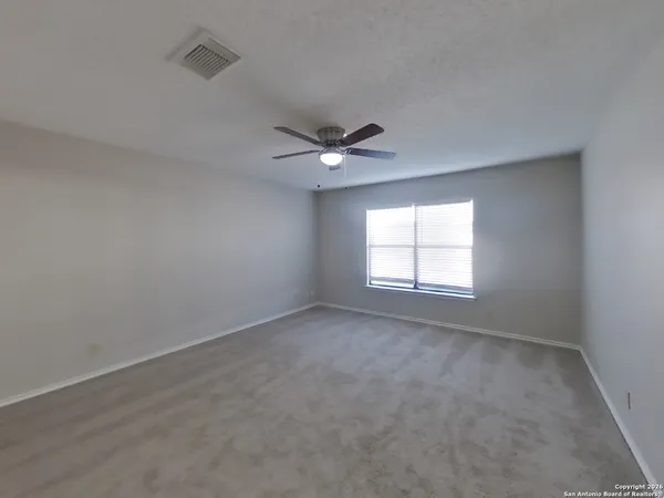 an empty room with a ceiling fan and window
