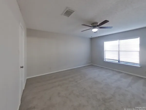 an empty room with a window and ceiling fan