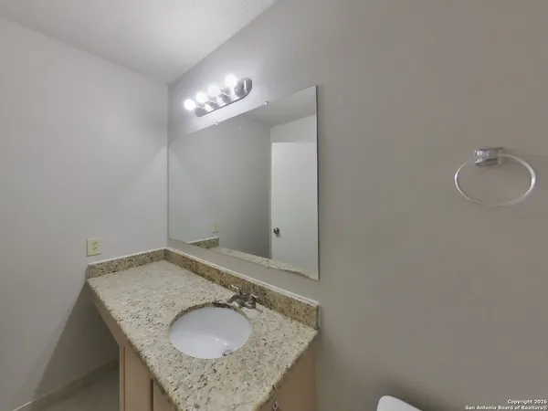 a bathroom with a granite countertop sink and a mirror