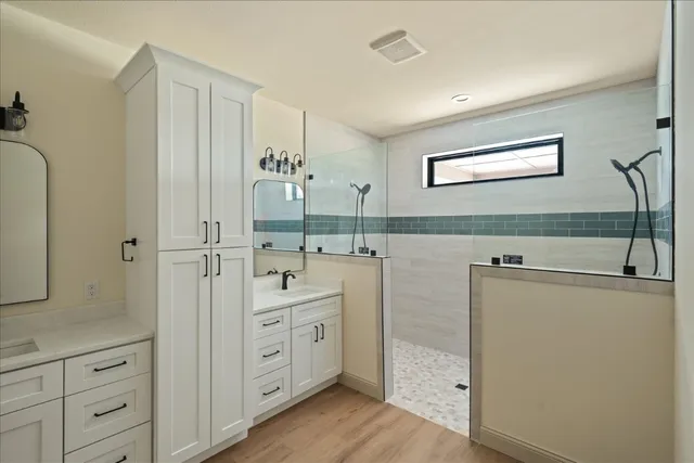 a spacious bathroom with a double vanity sink a mirror and a shower