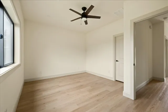 an empty room with wooden floor and a ceiling fan