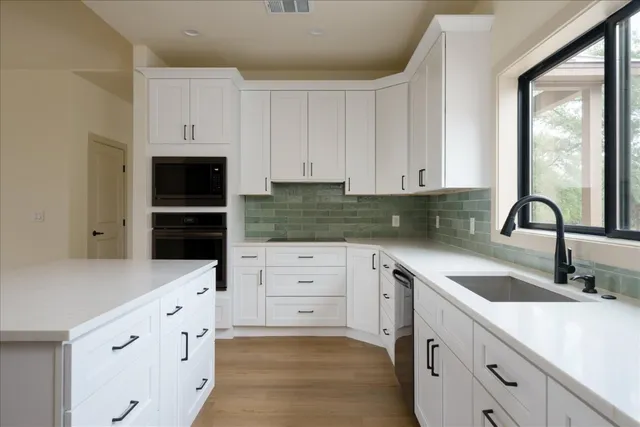 a kitchen with granite countertop white cabinets and stainless steel appliances