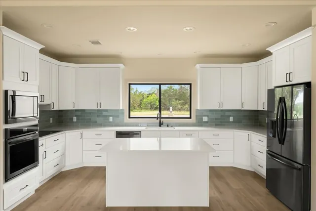 a kitchen with kitchen island white cabinets and refrigerator
