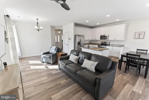 a living room with stainless steel appliances furniture and a kitchen view