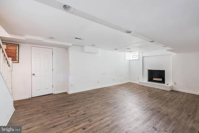 a view of empty room with wooden floor and fireplace
