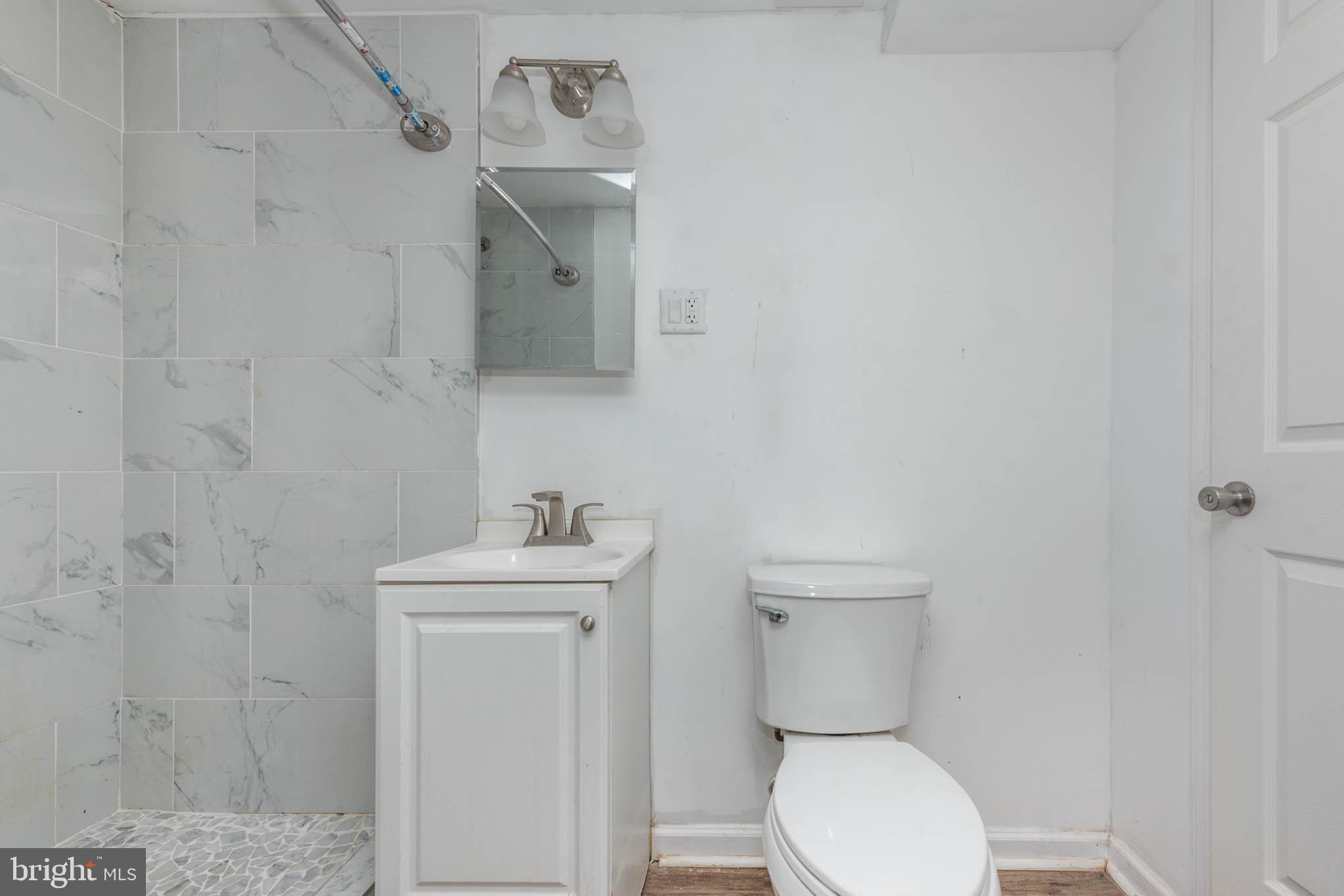 6702 Queens Ferry Road Baltimore, MD 21239 - Photo 31 of 40 a bathroom with a toilet sink and mirror