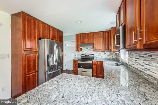a kitchen with granite countertop a refrigerator stove top oven a sink and dishwasher