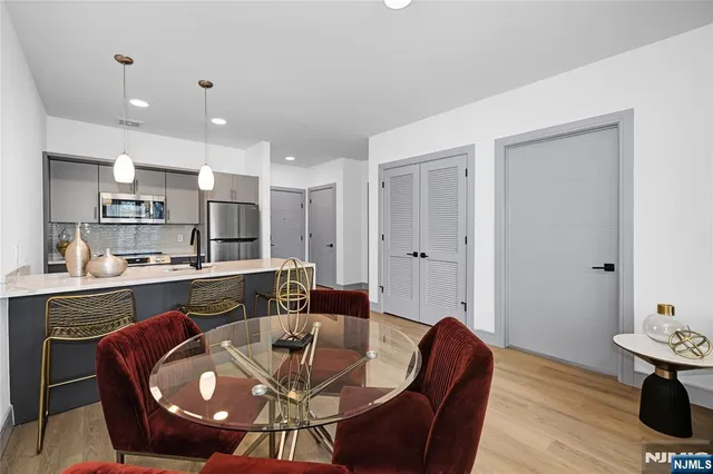 a living room with stainless steel appliances kitchen island granite countertop furniture and a wooden floor