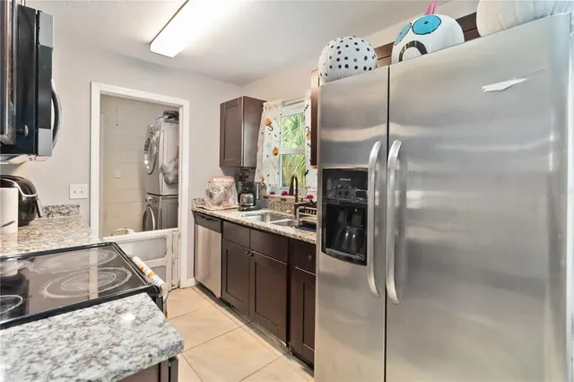 a kitchen with stainless steel appliances granite countertop a refrigerator a sink and white cabinets
