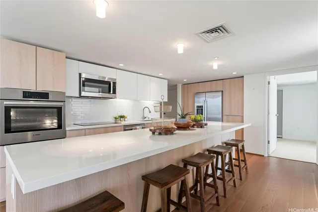 a kitchen with stainless steel appliances a stove a sink a microwave a dining table and chairs
