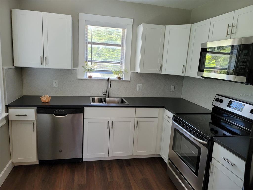 3301 West Woodlawn Avenue Tampa, FL 33607 - Photo 21 of 39 a kitchen with stainless steel appliances granite countertop white cabinets granite counter tops and a hard wood floors