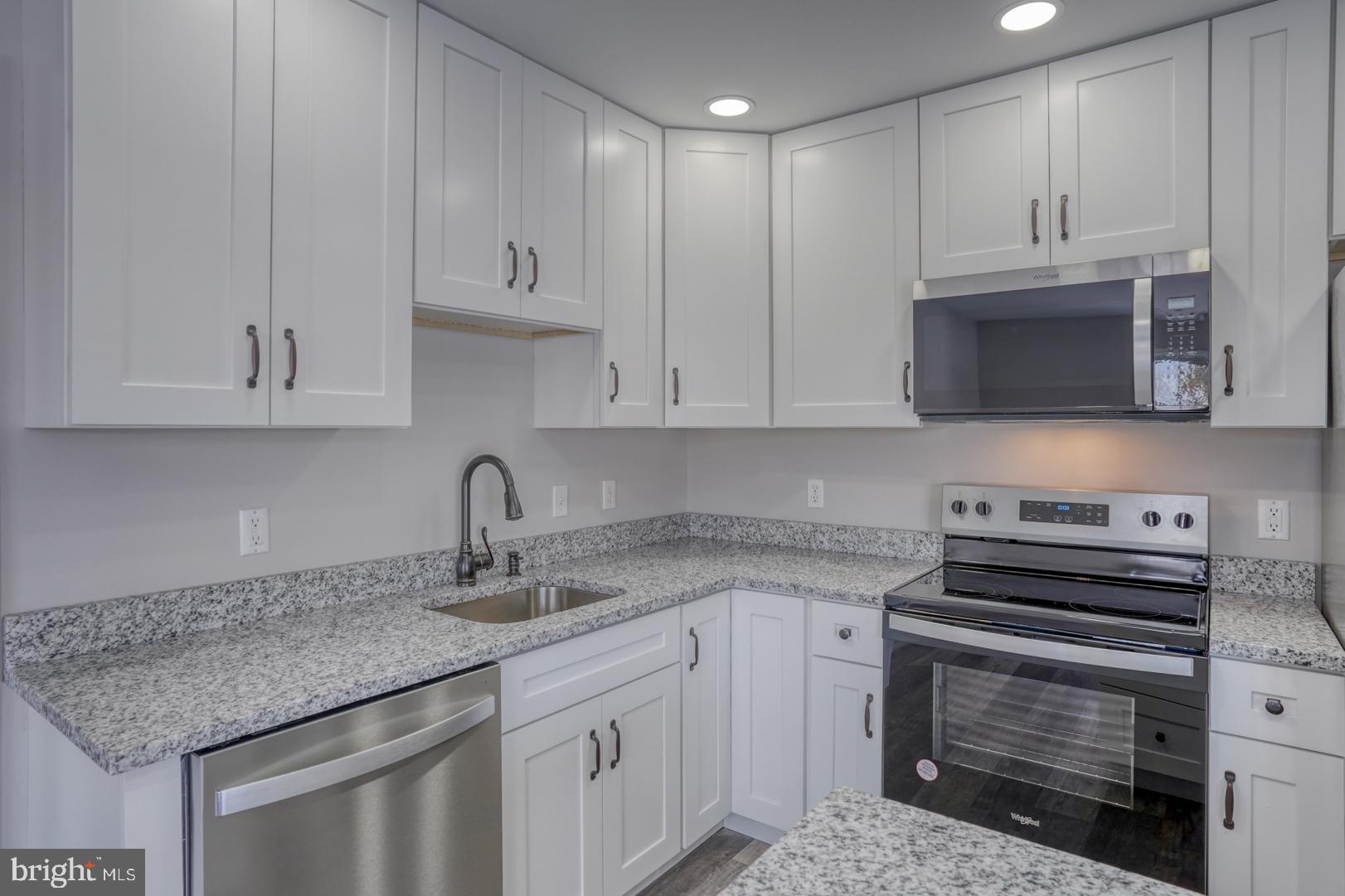 39 High Street Kenton, DE 19955 - Photo 31 of 49 a kitchen with stainless steel appliances granite countertop a sink dishwasher a stove and a microwave oven with white cabinets