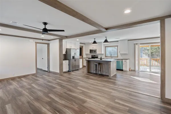 a view of empty room with wooden floor and fan