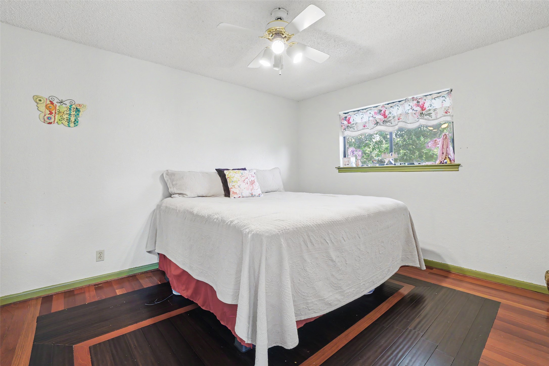 110 South Ridge Circle Georgetown, TX 78628 - Photo 21 of 37 Bedroom featuring a ceiling fan with light fixture, a window, and wood-finish flooring with a dark geometric inlay