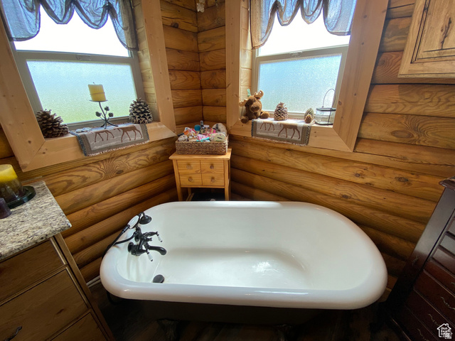 79 Auburn Forest Road Auburn, WY 83111 - Photo 30 of 76 Full bathroom with vanity, rustic walls, and a soaking tub