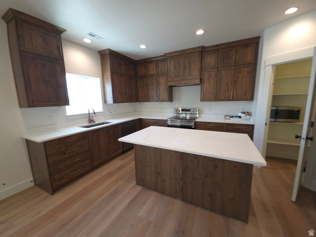 1267 West 2350 South Perry, UT 84302 - Photo 6 of 20 Open-concept kitchen featuring an island with a white countertop, wood-finish flooring, dark wood cabinetry, a stainless steel range, and recessed lighting