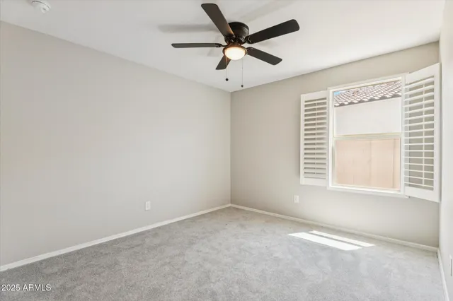 an empty room with a window and a fan