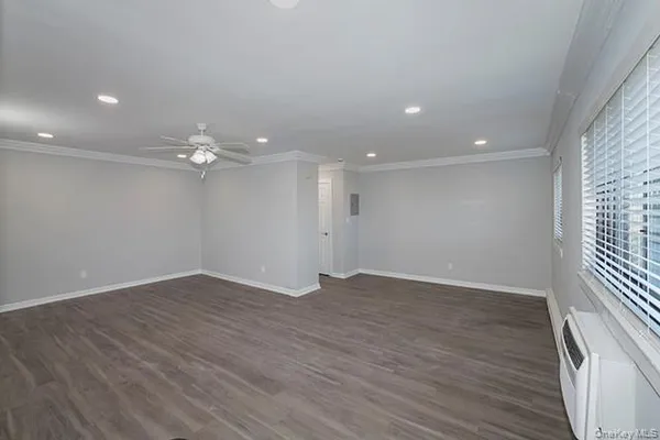 an empty room with wooden floor and ceiling fan