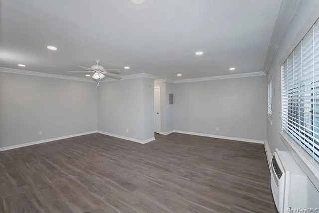 an empty room with wooden floor and ceiling fan