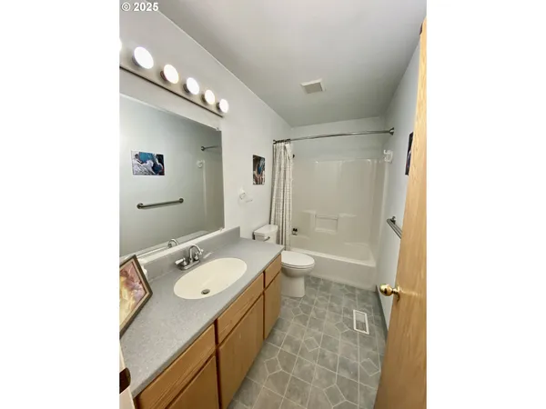 a bathroom with a granite countertop sink a toilet a mirror and shower
