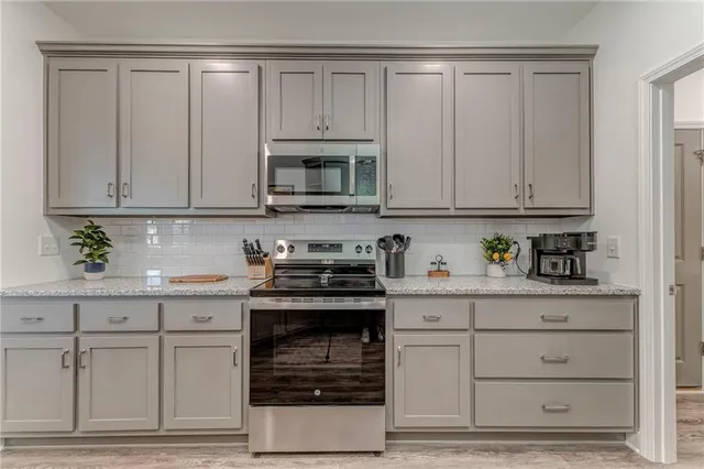 a kitchen with granite countertop white cabinets and stainless steel appliances