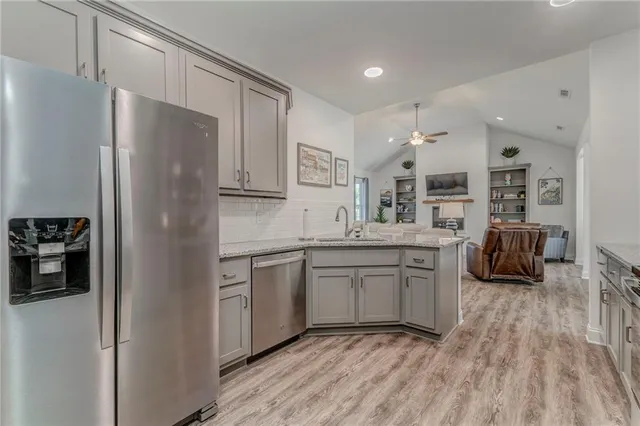 a kitchen with granite countertop a refrigerator stove top oven and sink