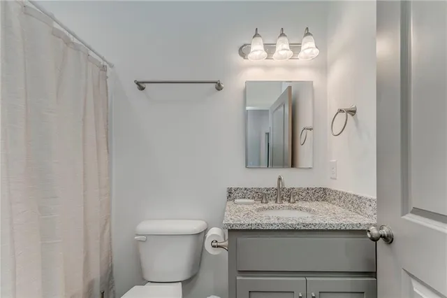 a bathroom with a granite countertop sink a toilet and a mirror