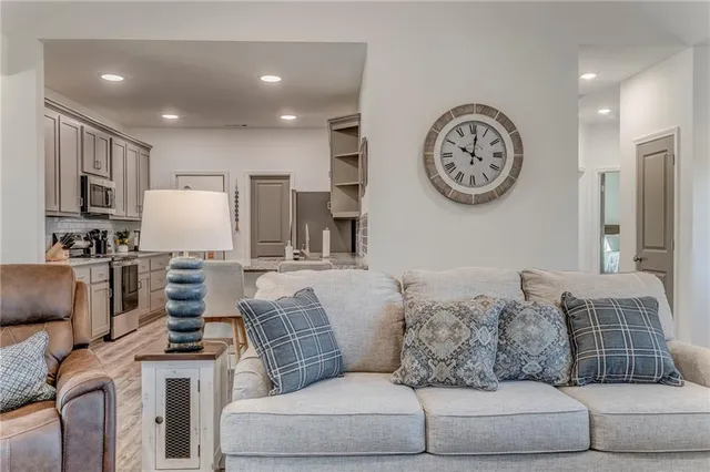a living room with furniture a clock and a view of kitchen