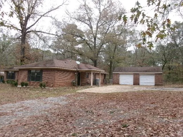 a front view of house with yard and trees in the background
