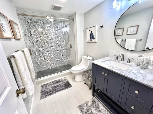 a bathroom with a sink a toilet a mirror a vanity and shower