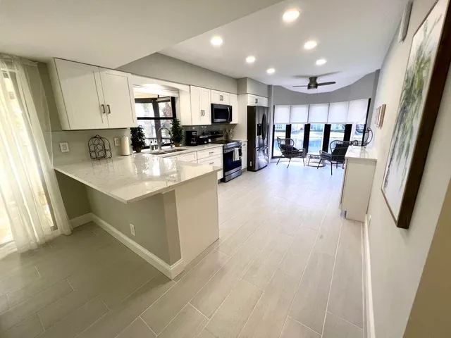 a large white kitchen with lots of counter top space a sink and appliances