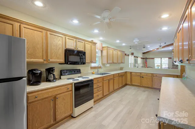 a kitchen with stainless steel appliances granite countertop a sink a stove top oven a refrigerator with grey cabinets and wooden floor