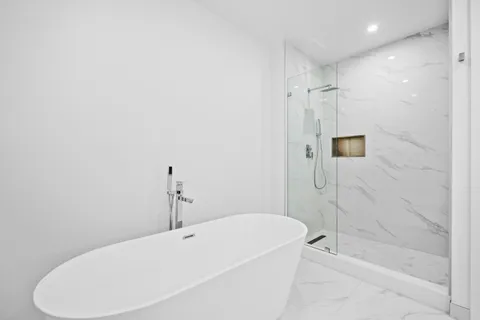 a bathroom with a white bath tub a shower and a sink