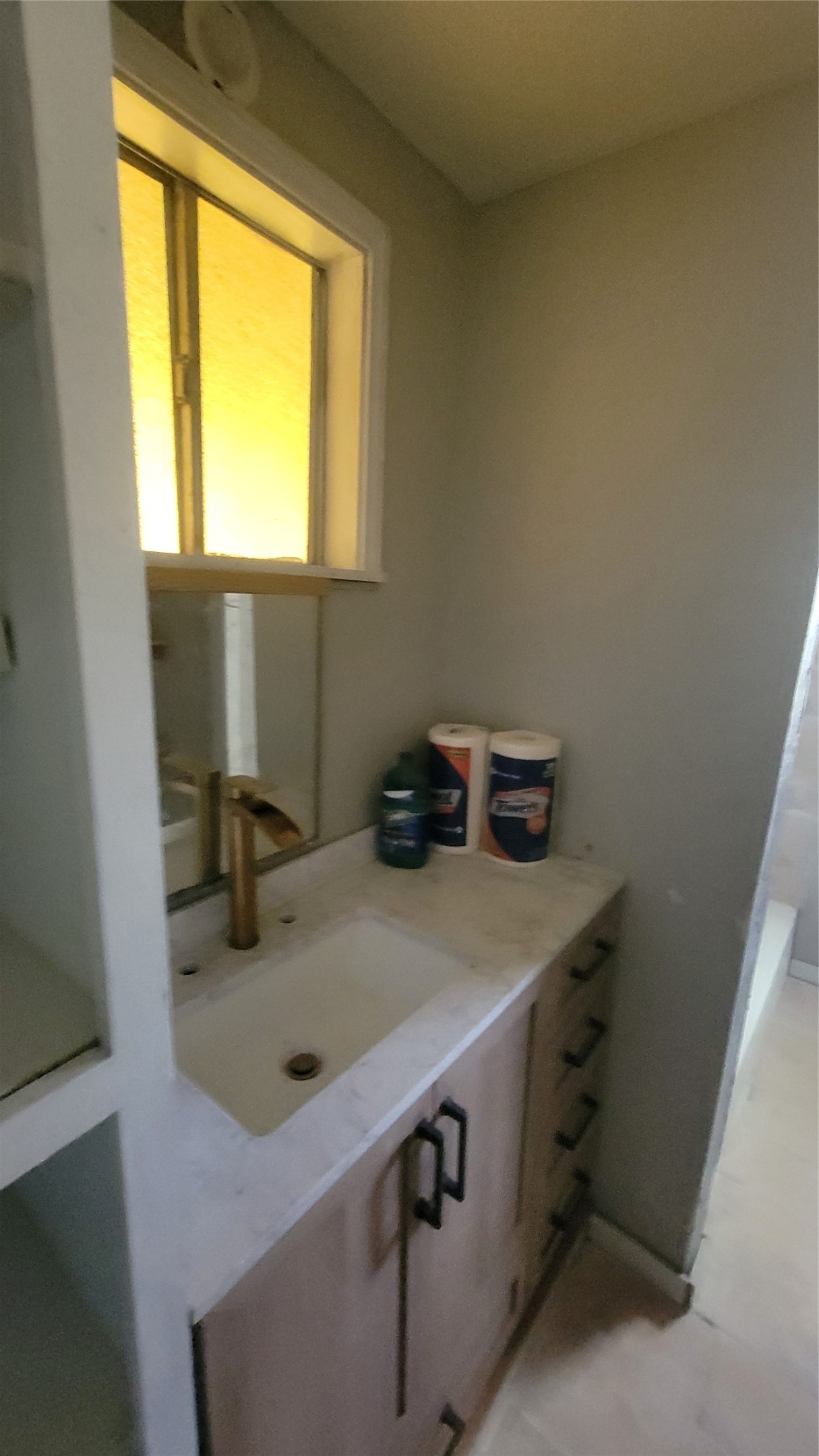 12018 Sandpiper Road Angleton, TX 77515 - Photo 25 of 48 This photo shows a compact bathroom vanity area with a single sink, modern faucet, and under-sink storage. A window above the sink provides natural light.