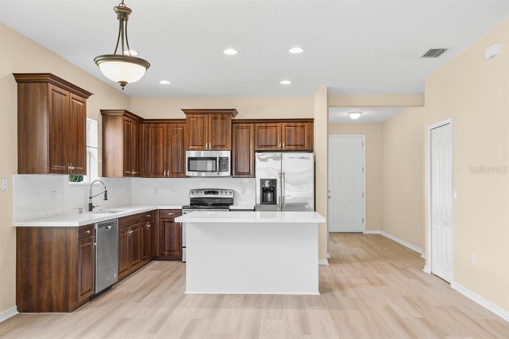 11790 Fennemore Way Parrish, FL 34219 - Photo 5 of 25 a kitchen with stainless steel appliances a sink a stove a refrigerator cabinets and wooden floor