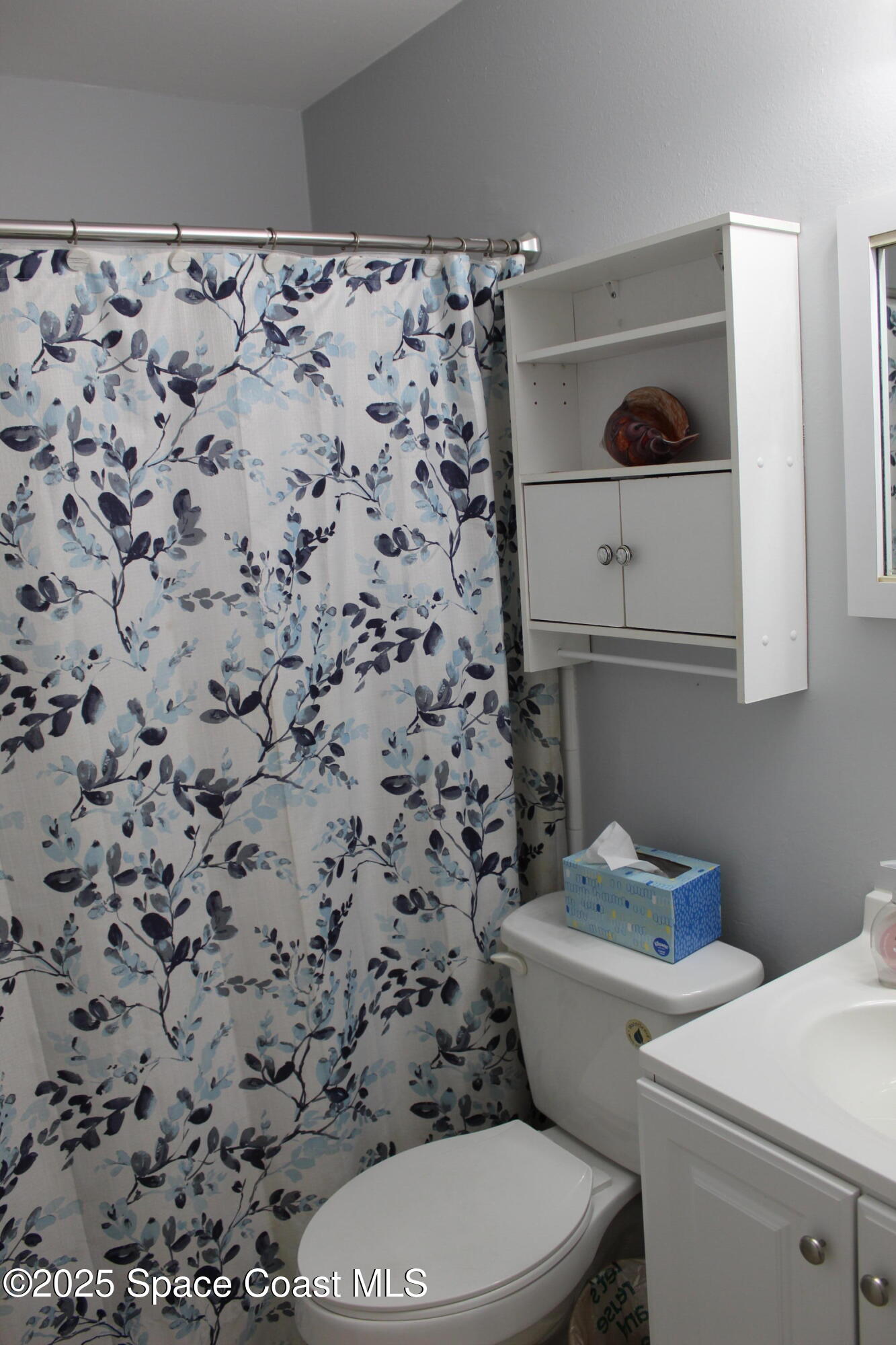 3150 North Atlantic Avenue, Unit 14880 Cocoa Beach, FL 32931 - Photo 12 of 13 a white toilet sitting next to a shower curtain