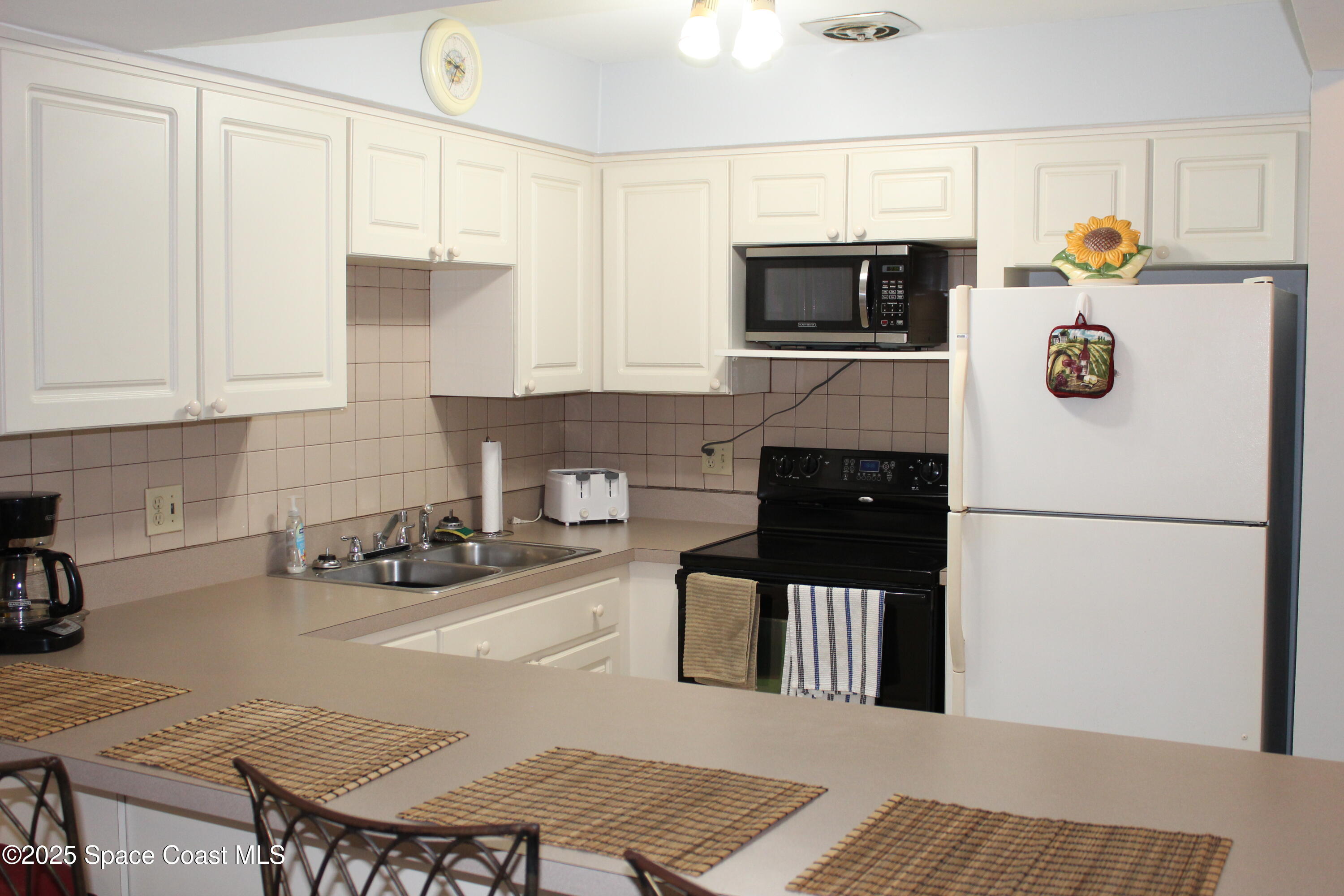 3150 North Atlantic Avenue, Unit 14880 Cocoa Beach, FL 32931 - Photo 2 of 13 a kitchen with a refrigerator a stove a microwave and sink