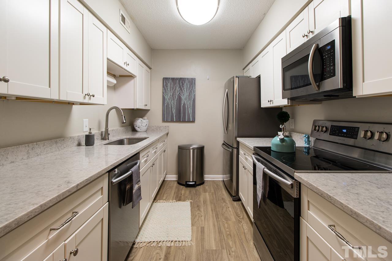 4711 Edwards Mill Road, Unit C Raleigh, NC 27612 - Photo 4 of 13 a kitchen with stainless steel appliances granite countertop a sink a stove a microwave a sink a refrigerator and cabinets