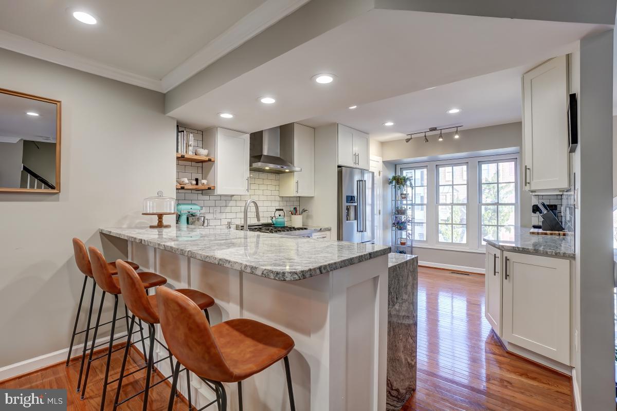 a kitchen with stainless steel appliances granite countertop a kitchen island and chairs in it