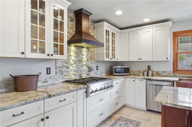a kitchen with stainless steel appliances granite countertop a stove a sink and white cabinets