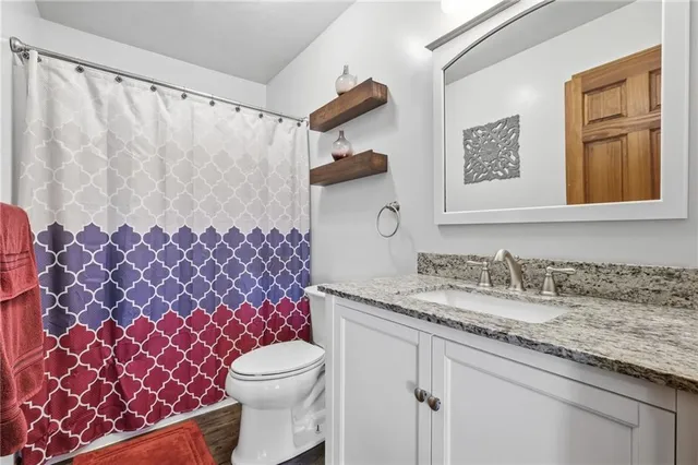 a bathroom with a granite countertop toilet sink and mirror