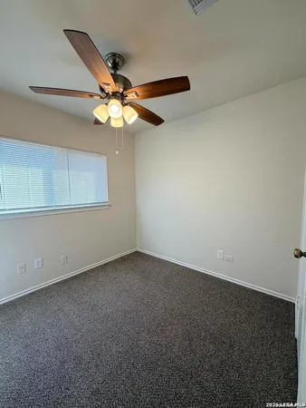 an empty room with a window and a fan