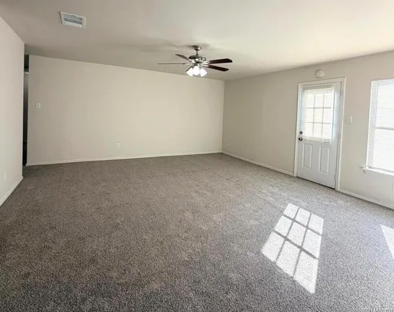 an empty room with windows and ceiling fan