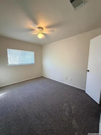 an empty room with a ceiling fan and a window